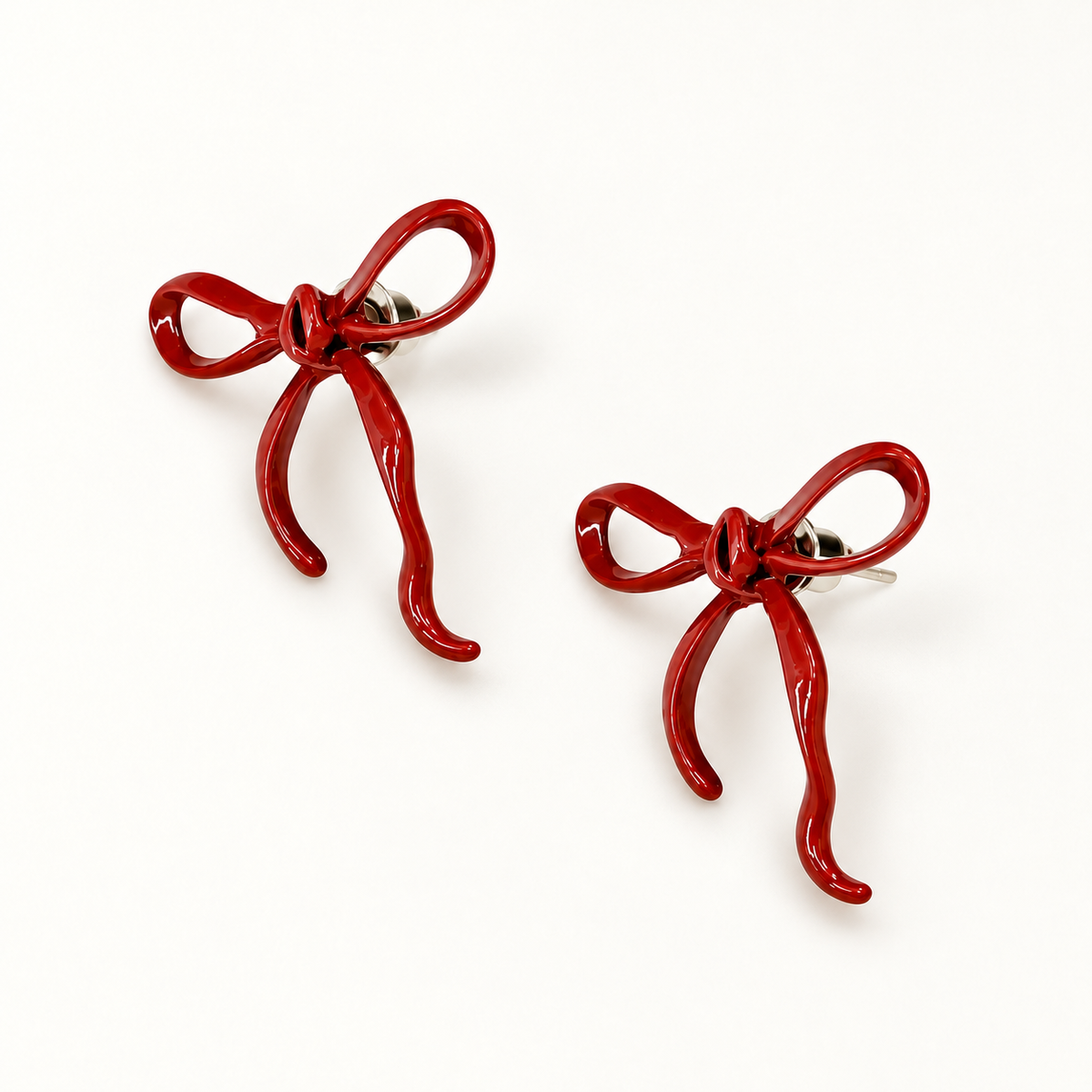 A pair of glossy deep-red open-loop bow stud earrings on a clean light background.